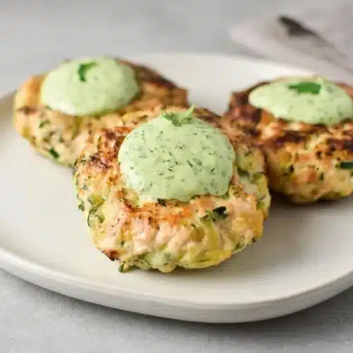 Golden brown chicken zucchini poppers stacked on a plate with tender centers and seared edges.