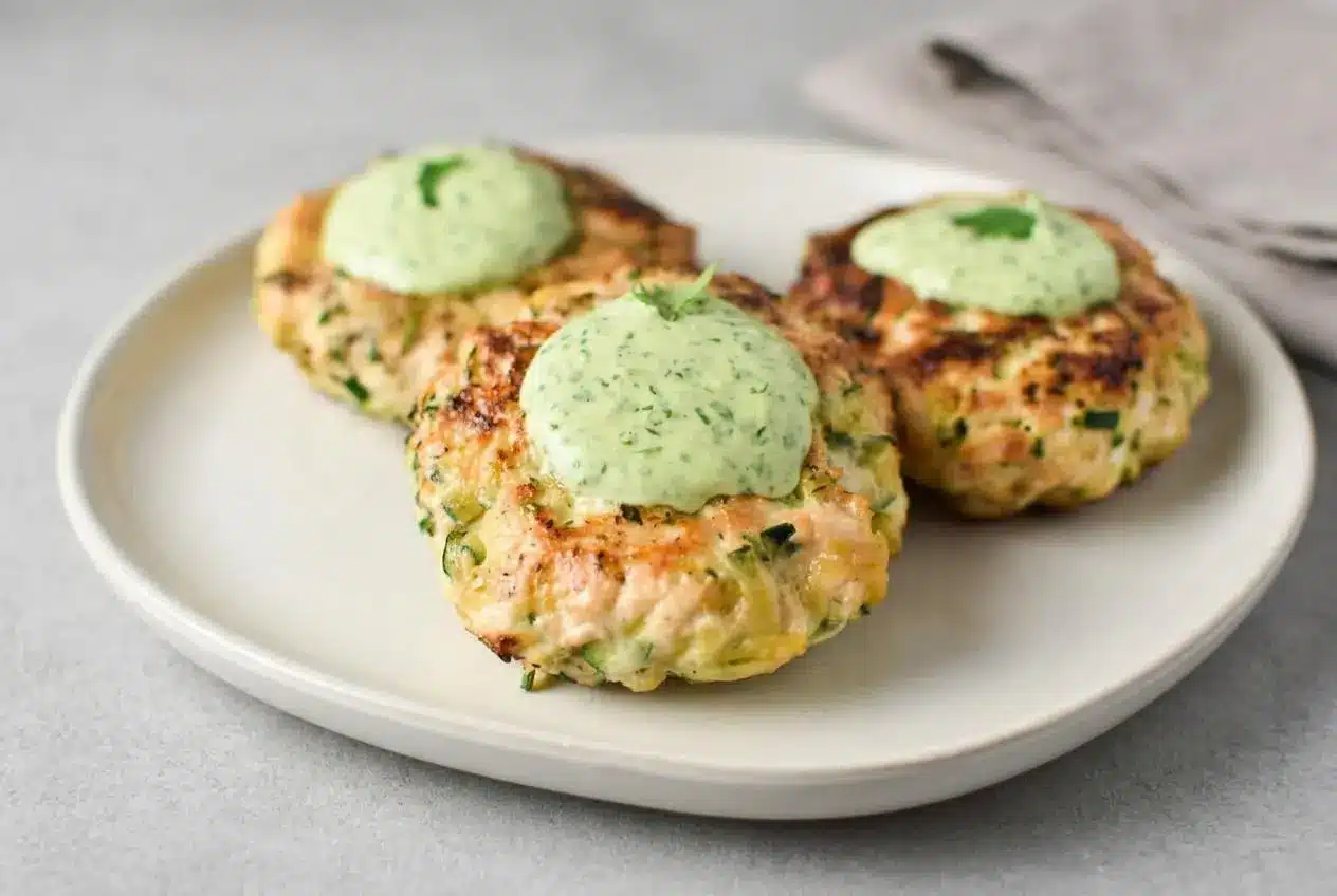Golden brown chicken zucchini poppers stacked on a plate with tender centers and seared edges.