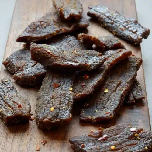 Beef jerky recipe featuring chewy, savory dark mahogany dried beef strips with cracked black pepper.
