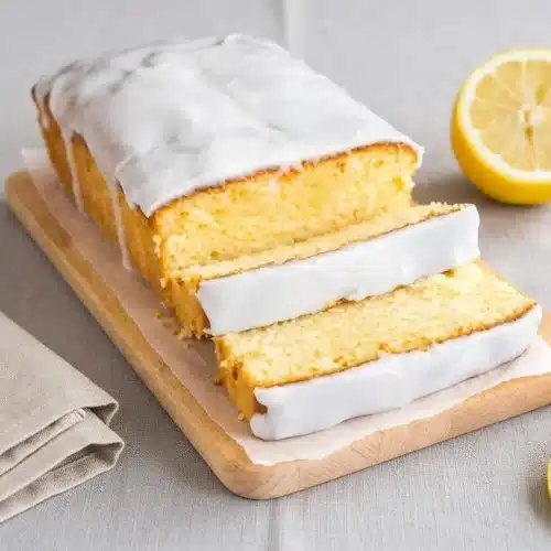 Glazed lemon loaf cake with a thick white icing drip and velvety crumb