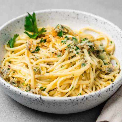 Linguine with clam sauce featuring tender baby clams, fresh parsley, and a glossy garlic white wine emulsion.