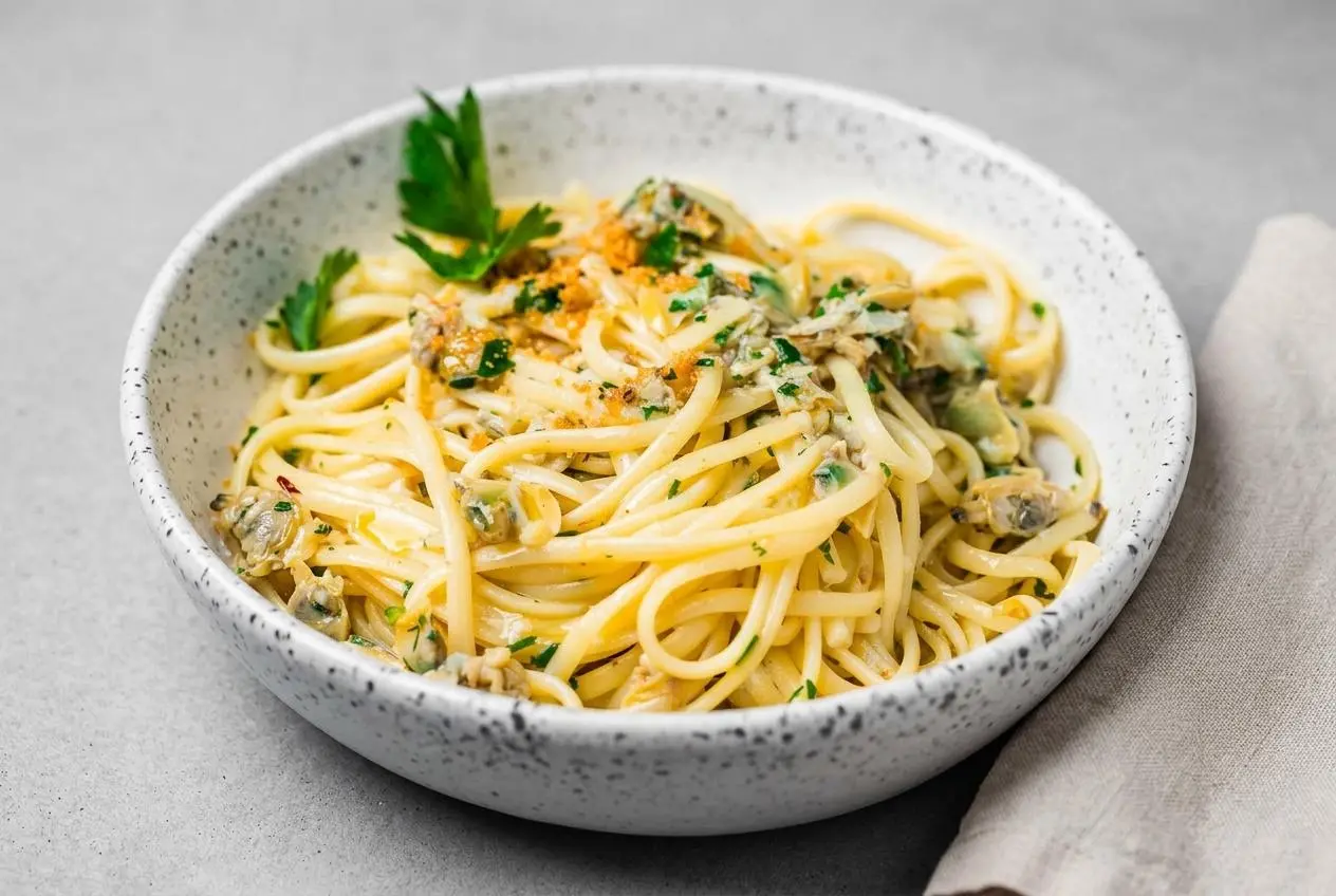 Linguine with clam sauce featuring tender baby clams, fresh parsley, and a glossy garlic white wine emulsion.