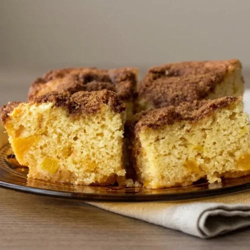 Golden mango coffee cake baked in a pan with tender fruit chunks and cinnamon sugar topping.