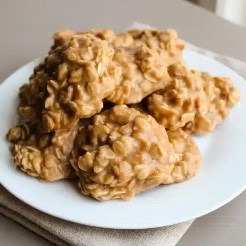 No bake peanut butter oatmeal cookies piled with a golden, glossy finish and visible chewy rolled oats.