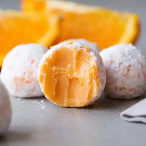 Orange creamsicle truffles dusted in fine powdered sugar with a velvety citrus ganache center.