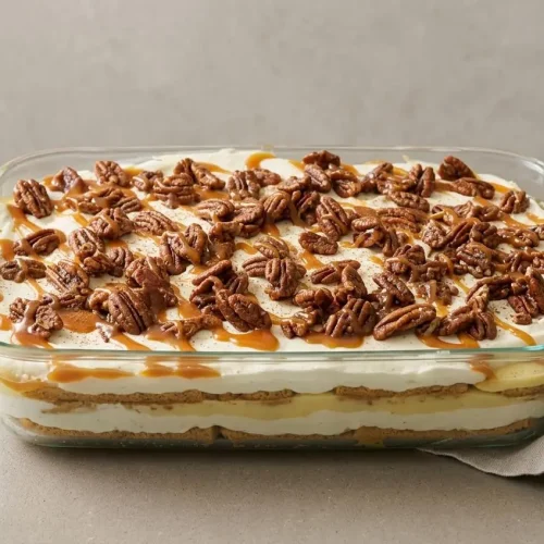 Pecan pie lasagna layered with pudding, cream cheese, and glossy caramel pecans.