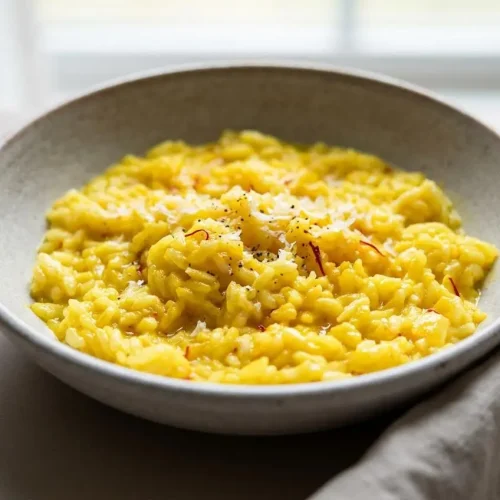 Creamy golden Saffron Risotto served in a shallow bowl with a glossy finish.