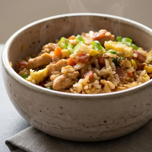 Fluffy chicken fried rice with glossy soy-glazed grains, tender chicken, soft scrambled eggs, and peas.