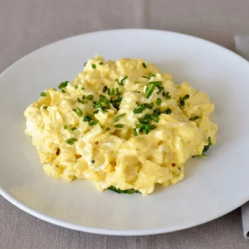 Velvety scrambled eggs with cream cheese showing tender golden curds and melted cheese pockets.
