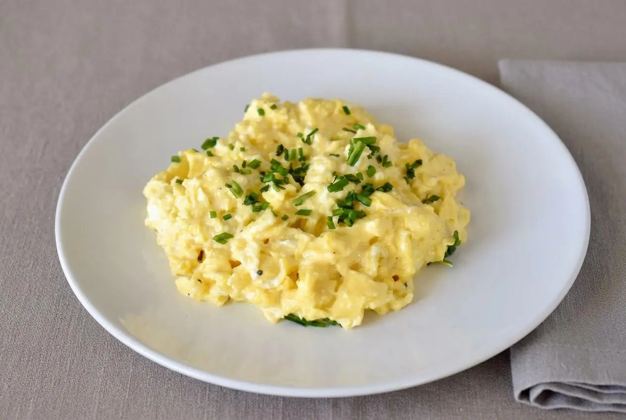 Velvety scrambled eggs with cream cheese showing tender golden curds and melted cheese pockets.