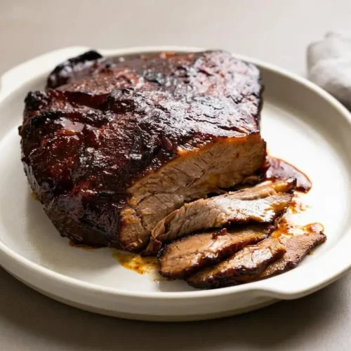 Slow cooker brisket recipe featuring tender sliced beef with a glossy caramelized barbecue glaze.