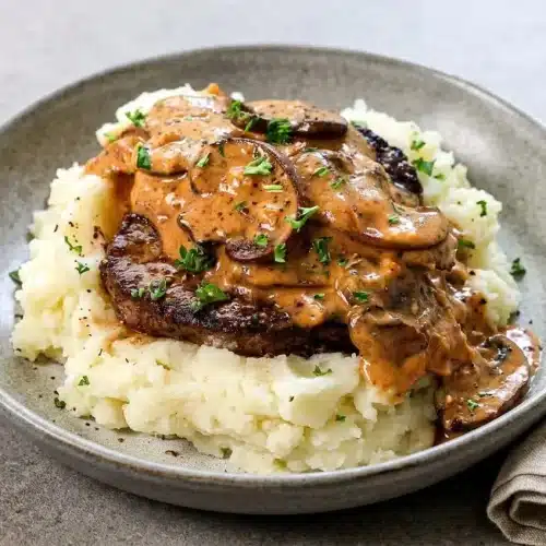 Seared steak diane medallions coated in glossy Dijon mushroom cream sauce with fresh parsley.