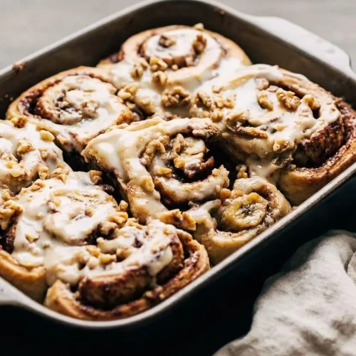 Warm banana bread cinnamon rolls with melting maple cream cheese icing, cinnamon swirls, and chopped walnuts