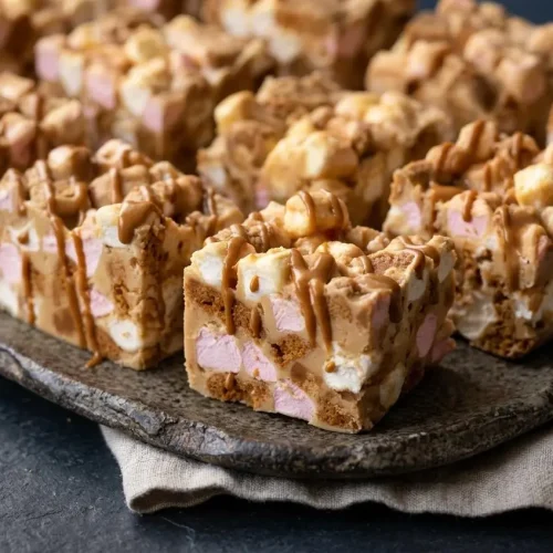 Thick bars of biscoff rocky road with a creamy white chocolate coating, chunky cookies, mini marshmallows, and fudge pieces.