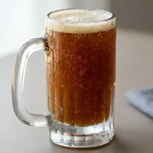 Chilled rye bread kvass recipe poured into a tall glass with rising bubbles and a delicate beige foam head.