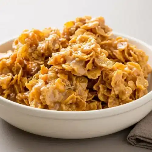 Chewy peanut butter cornflake cookies with glossy amber coating and crisp cereal edges.