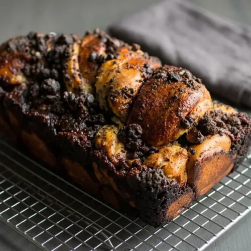 Freshly baked chocolate babka loaf with a glossy syrup finish, cocoa streusel topping, and dark fudge swirls.