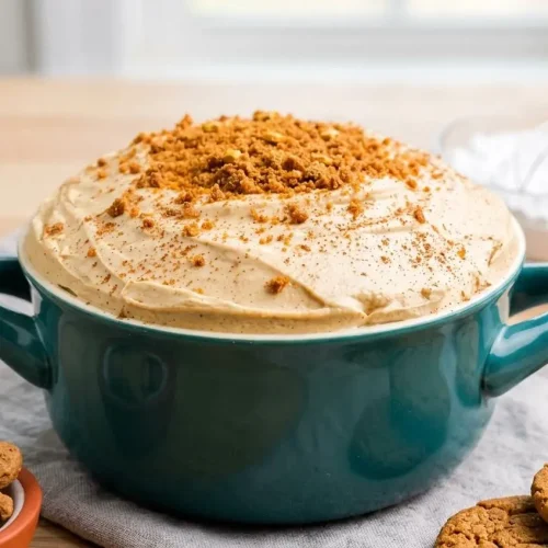 Bowl of creamy gingerbread cheesecake dip topped with crumbled gingersnap cookies and warm spices