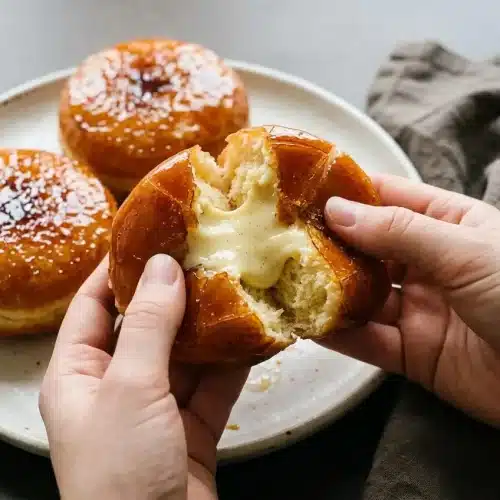 Homemade creme brulee donuts topped with a glossy amber caramel shell and filled with silky vanilla custard.
