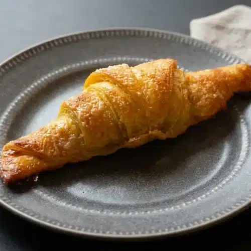 Freshly baked rice paper croissants with a blistered, golden sugar crust and plump crescent shape.