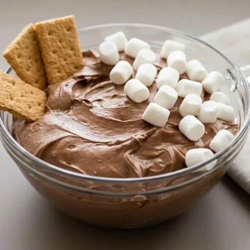 Fluffy hot chocolate dip topped with mini marshmallows in a bowl, showcasing a velvety gloss.