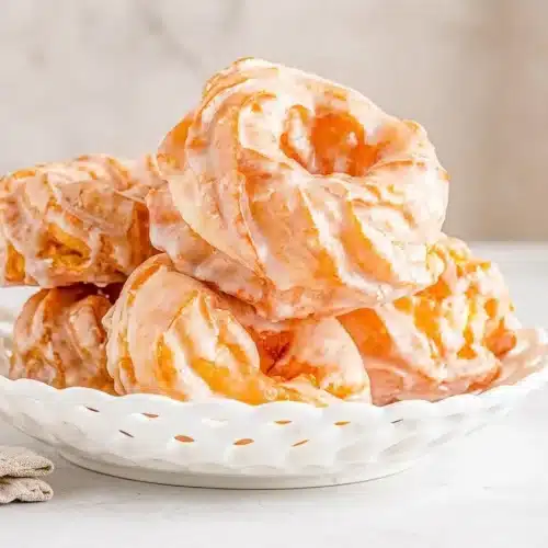 Golden french crullers with deep fluted ridges and a glossy vanilla glaze.
