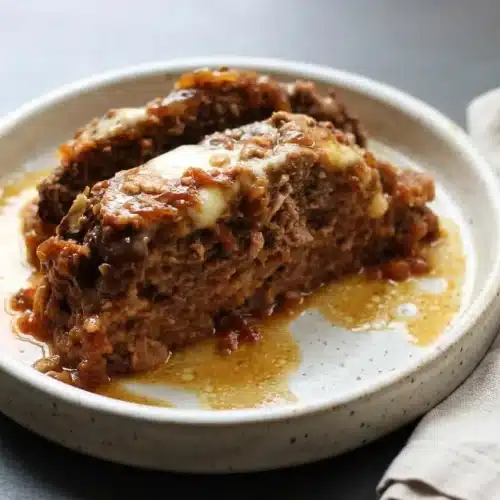 Tender french onion meatloaf topped with melted Swiss cheese over golden caramelized onions and rich broth.