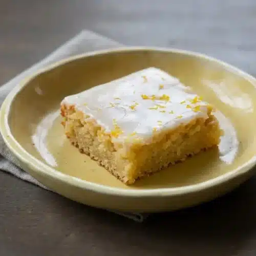Sliced lemon brownies with a dense pale-yellow crumb, glossy white chocolate glaze, and fresh lemon zest on top.