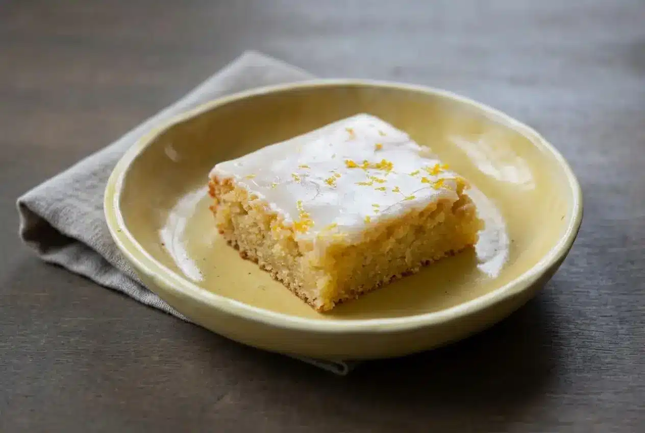 Sliced lemon brownies with a dense pale-yellow crumb, glossy white chocolate glaze, and fresh lemon zest on top.