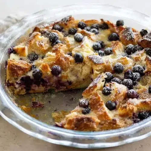 Baked blueberry croissant puff with golden flaky pastry tips, juicy blueberries, and creamy lemon custard