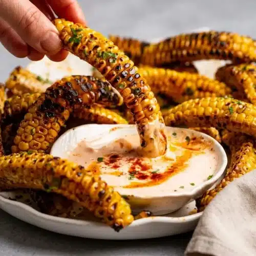 Platter of tender grilled corn ribs with charred kernels and a glossy garlic butter glaze.