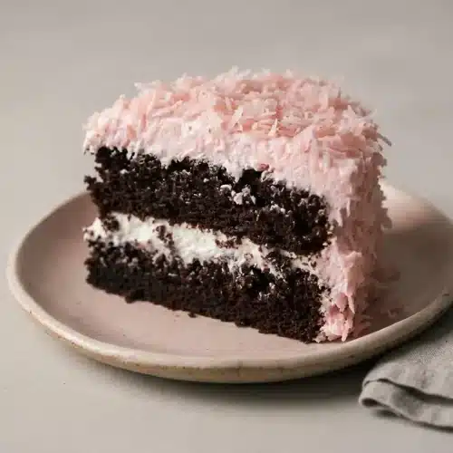 Hostess snowball cake recipe with moist chocolate layers, billowy marshmallow frosting, and chewy pink coconut coating