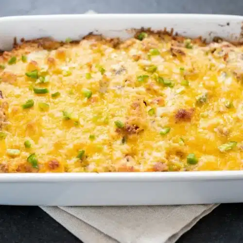 Baked jalapeno popper chicken casserole recipe in a 9x13 dish with a golden bubbly cheddar topping, bacon, and jalapenos.