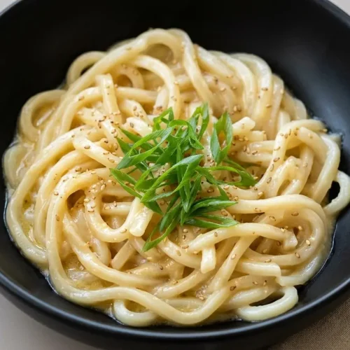 Chewy miso butter noodles coated in a silky, glossy sauce garnished with green onion and sesame seeds.