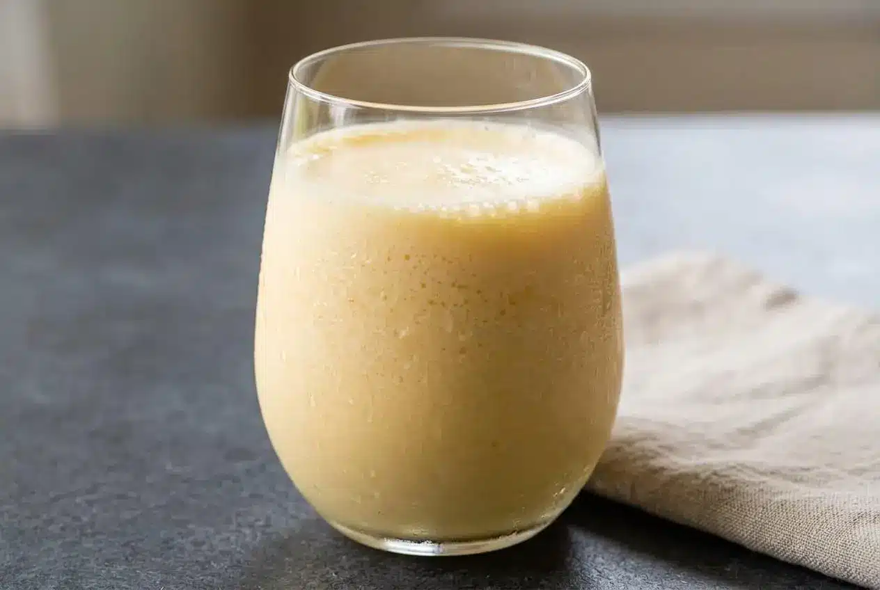 Chilled glass of homemade orange julius recipe with pale pastel orange slush and a thick white frothy top.