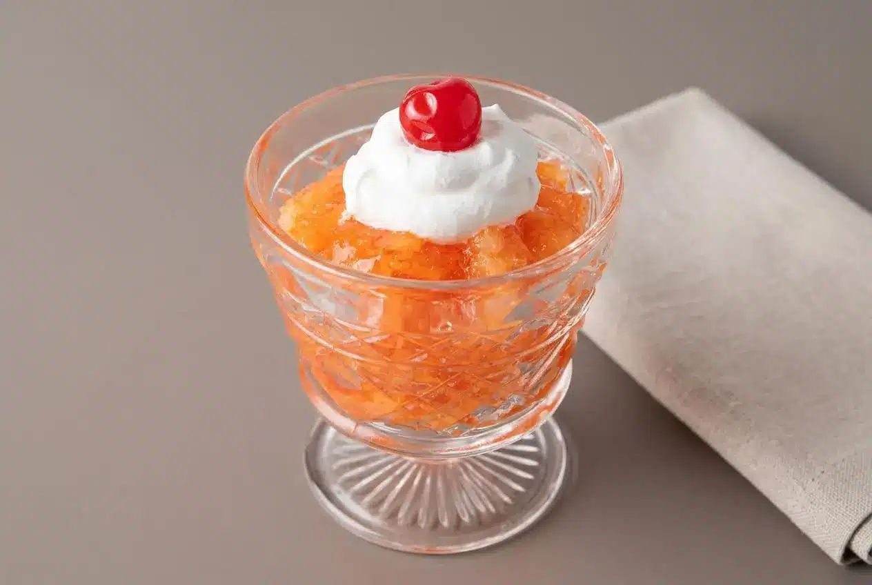 Pineapple Carrot Jello Salad with glossy orange gelatin and finely shredded carrots unmolded on a platter.