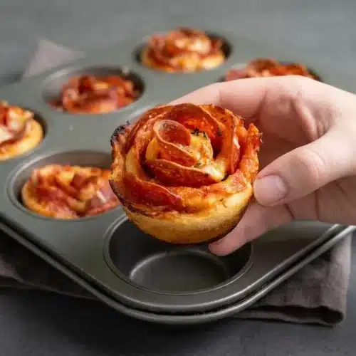 Baked pizza roses with crispy pepperoni petals, melted mozzarella, and golden-brown dough spirals.