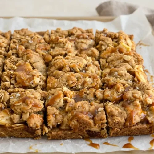 Salted caramel apple pie bars with a golden rolled oat crumble, thinly sliced spiced apples, and glossy caramel.