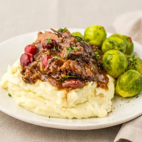 Slow Cooker Cranberry Beef Roast shredded in glossy sweet-savory gravy with soft cranberries.