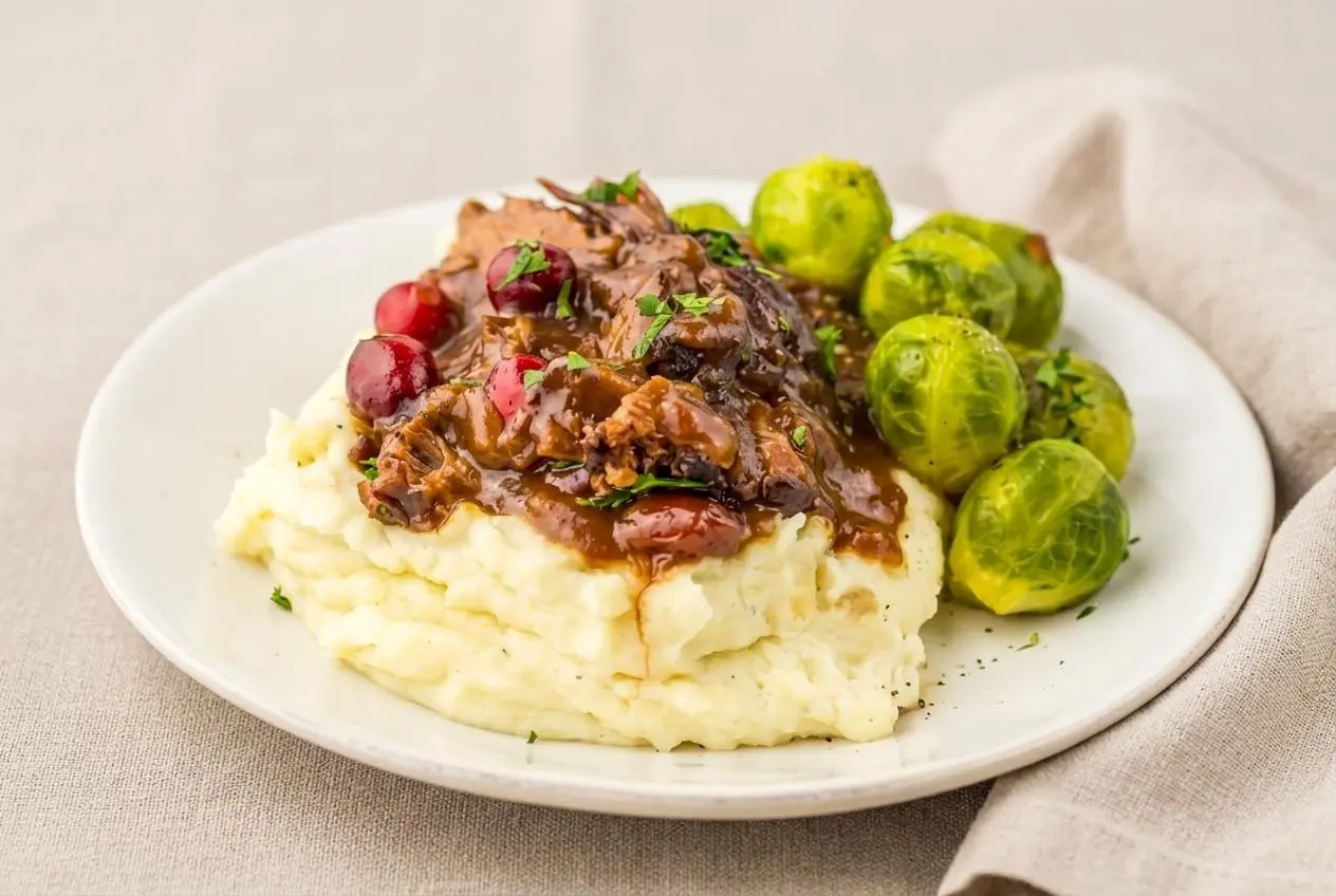 Slow Cooker Cranberry Beef Roast shredded in glossy sweet-savory gravy with soft cranberries.