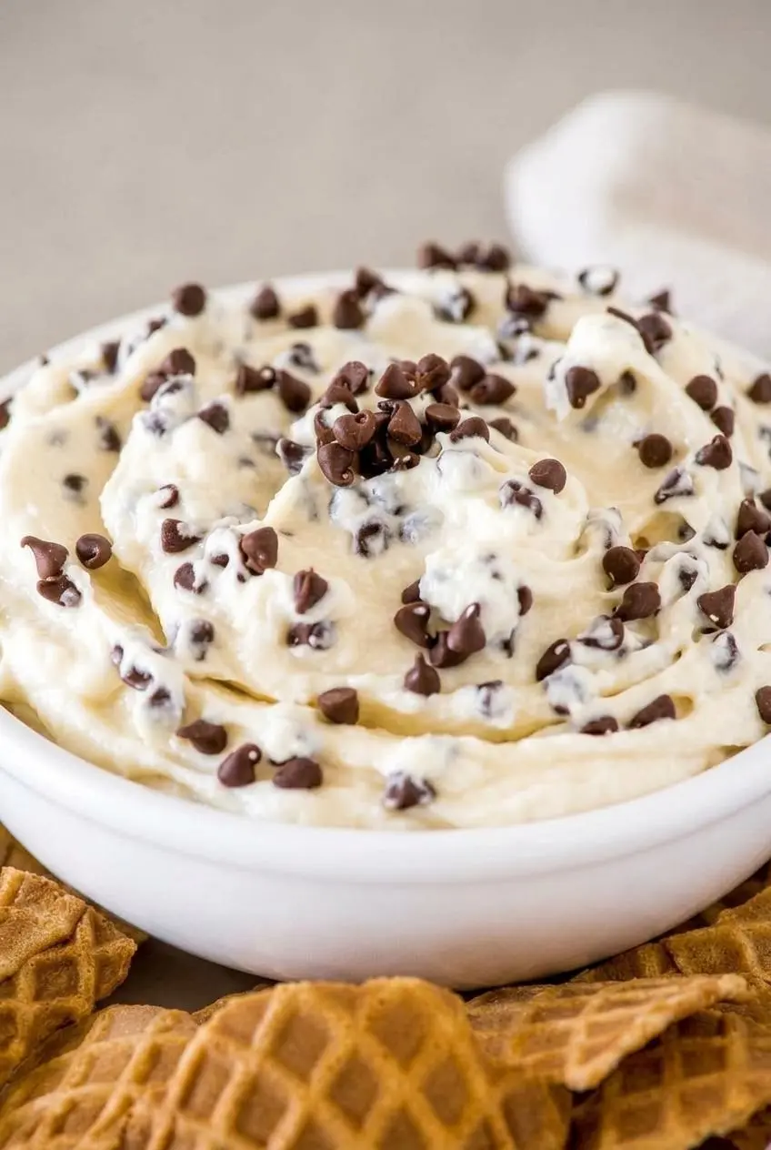 Close-up of thick cannoli dip scooped with a crisp waffle cone shard showing a smooth, non-watery texture.