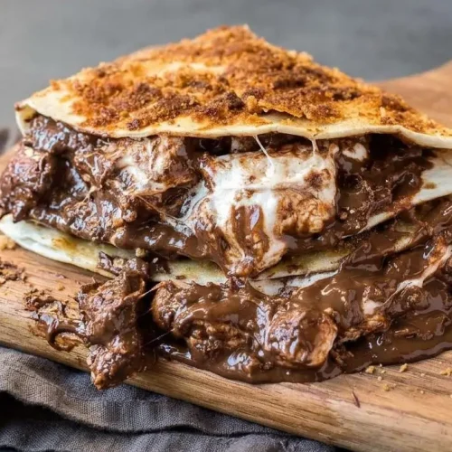 Warm s’mores quesadillas sliced into wedges with a golden graham cracker crust, melted chocolate, and gooey marshmallows.