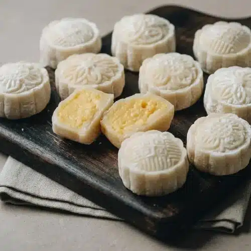 Chilled snow skin mooncakes with stamped pale white wrappers and a creamy golden egg custard filling