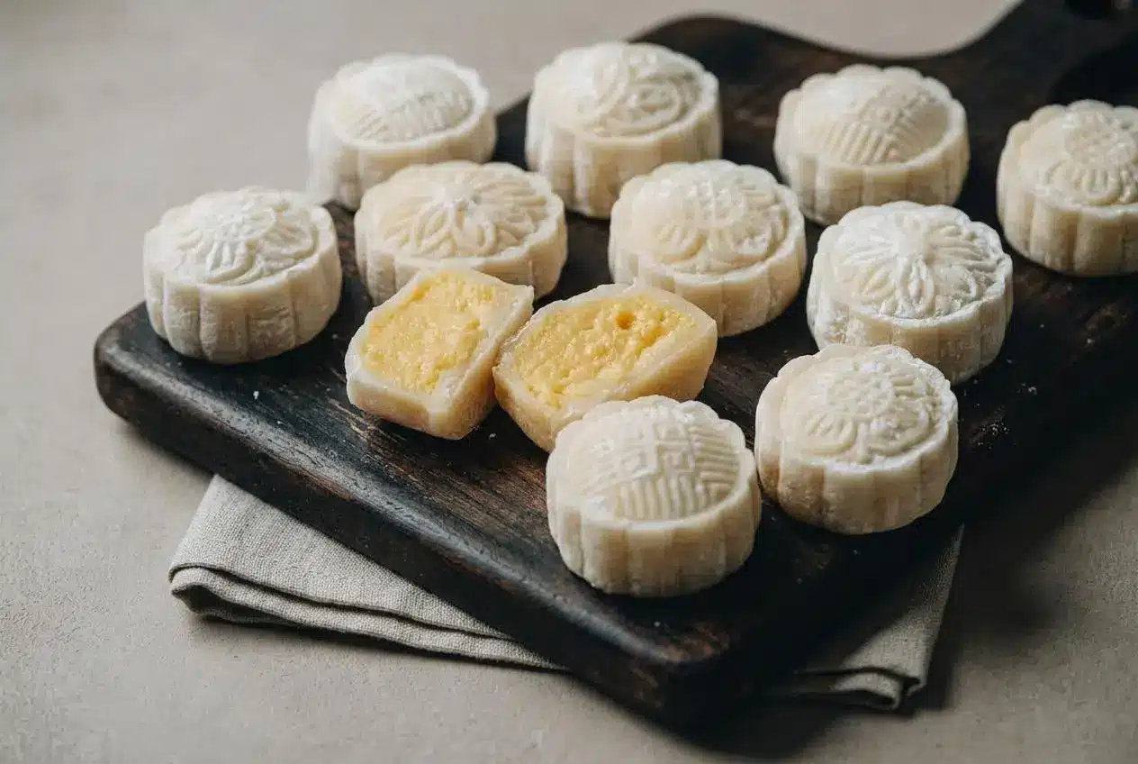 Chilled snow skin mooncakes with stamped pale white wrappers and a creamy golden egg custard filling