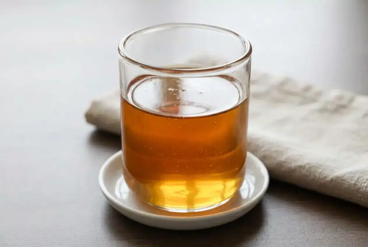 Glass bottle of golden-amber Sugar Cookie Latte Syrup with a clear, glossy finish on a kitchen surface