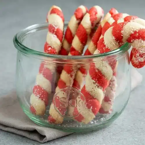 Baked red and white twisted candy cane cookies topped with sparkling crushed peppermint sugar.