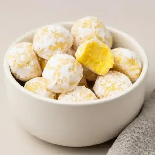 White chocolate lemon truffles dusted with fine powdered sugar on a serving platter.