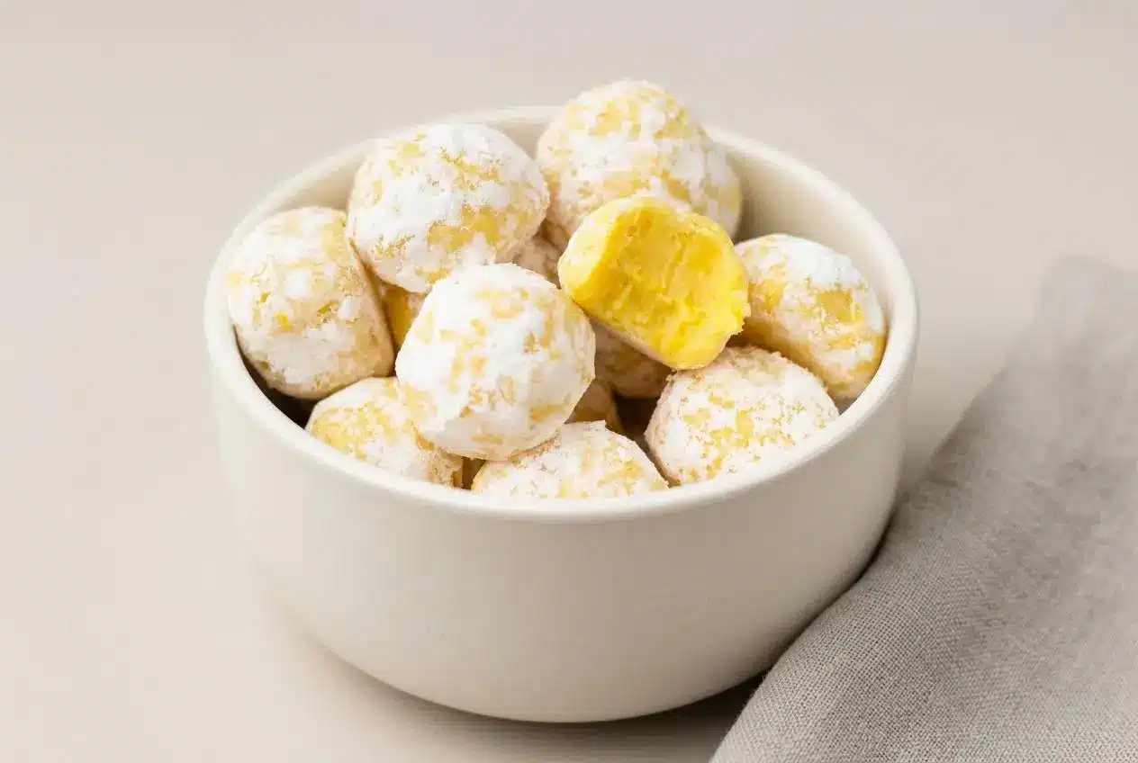 White chocolate lemon truffles dusted with fine powdered sugar on a serving platter.